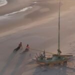 Kitesurfers and a traditional jangada sailboat on Parajuru beach
