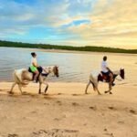 Two riders on horseback along the beach of Parajuru in Ceará