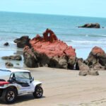 Beach buggy in front of the red cliffs of the Ceará coast