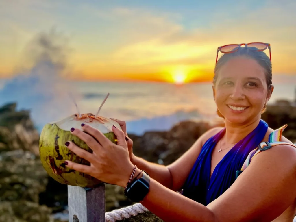 Priscilla drinking from a fresh coconut at sunset