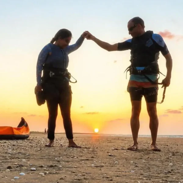 Two kitesurfers walking back along the beach at sunset in Parajuru, Ceará