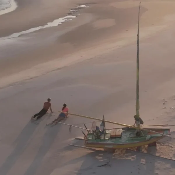 Kitesurfers and a traditional jangada sailboat on Parajuru beach
