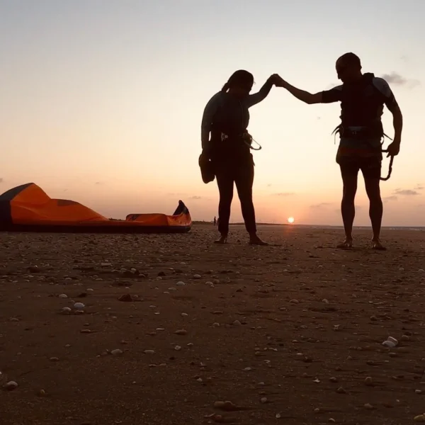 Kitesurfers silhouetted on the beach at sunset
