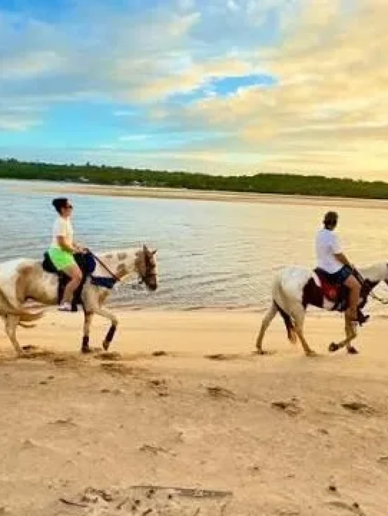 Two riders on horseback along the beach of Parajuru in Ceará